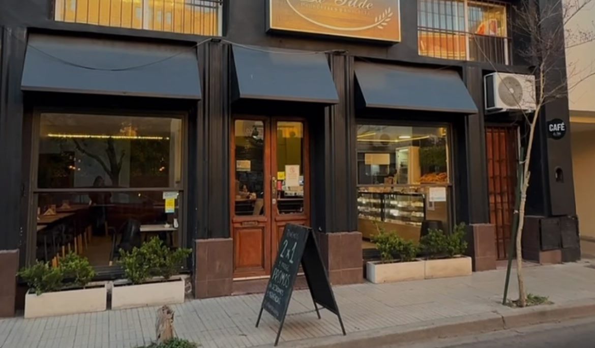 Fachada de La Tilde en Rivadavia 1080: frente negro con toldos, puerta de madera, vidriera con la vitrina y pizarra de promos en la vereda.